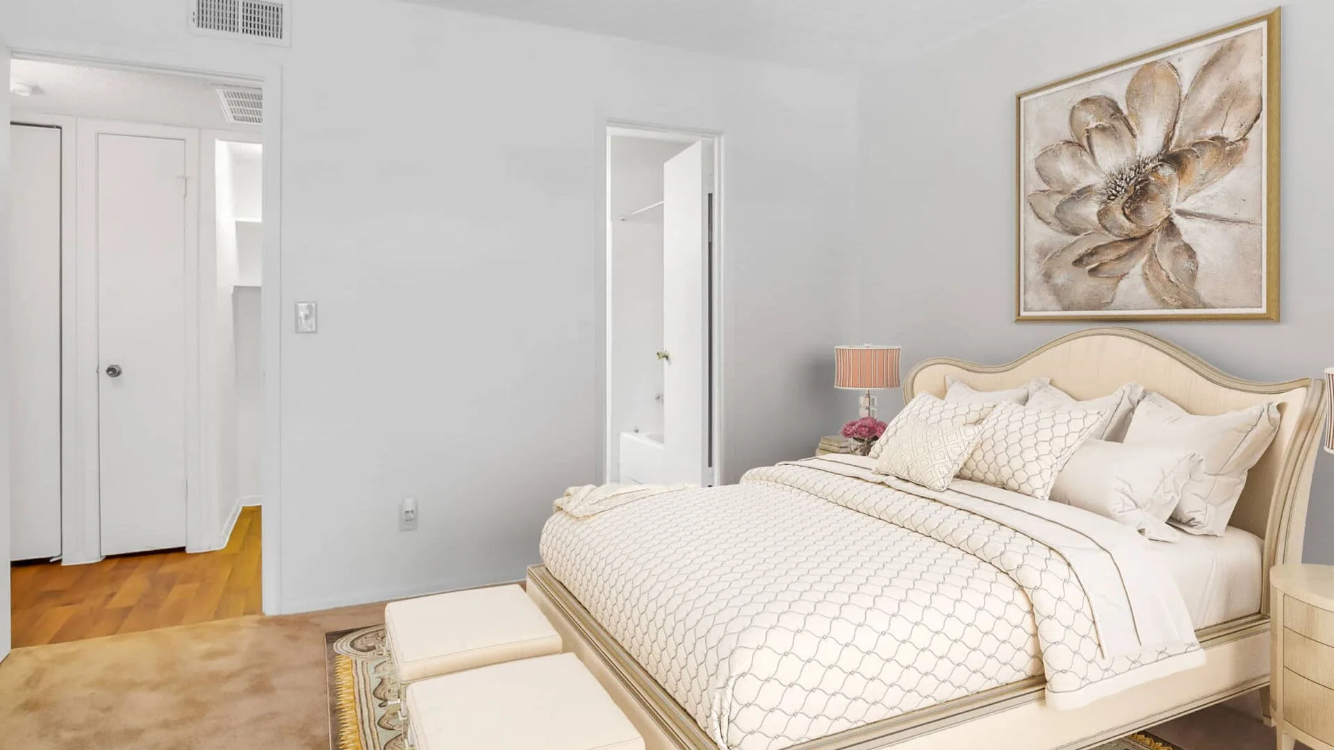 Bright bedroom with a tufted headboard, floral art and an open closet