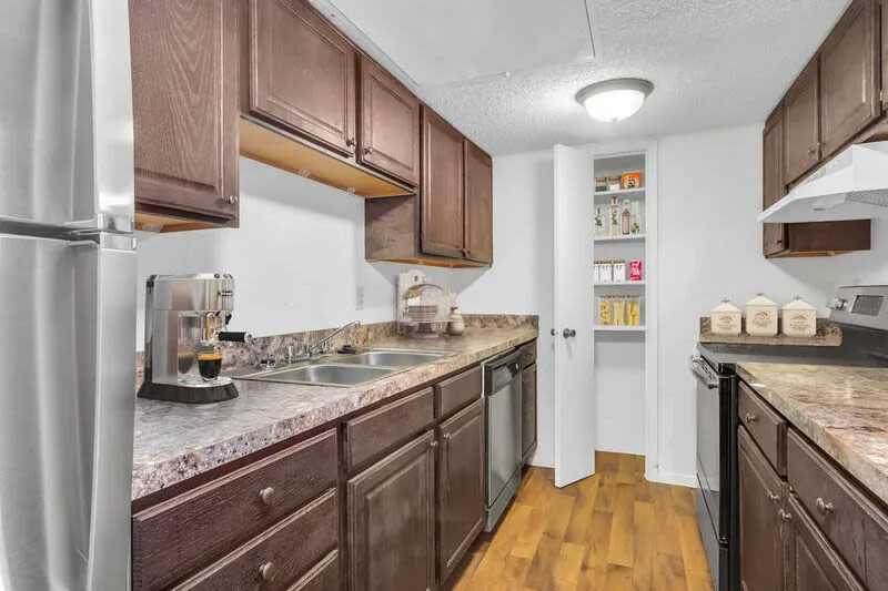 Galley kitchen with dark wood cabinets, stainless steel appliances and a pantry