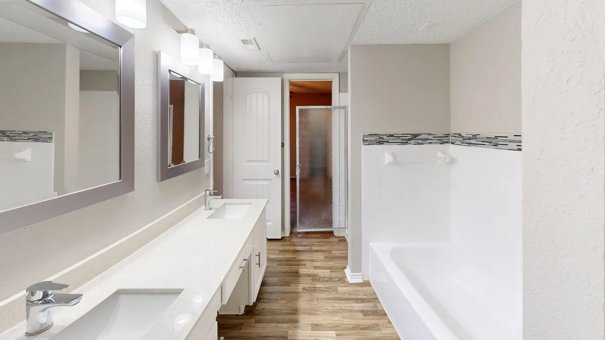 Dual-vanity bathroom with a soaking tub, walk-in shower, and mosaic tile accent