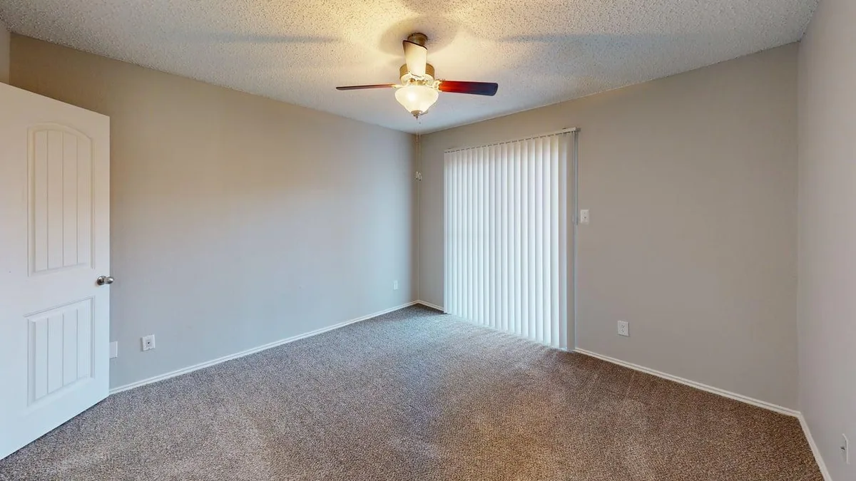 Carpeted bedroom with a sliding glass patio door and ceiling fan