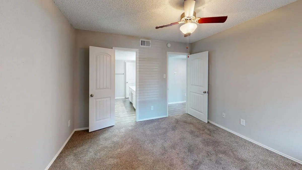 Carpeted bedroom with doors opening to an ensuite bath and walk-in closet