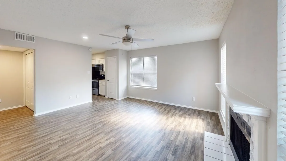 Open living and dining area with a corner fireplace and wood-look flooring