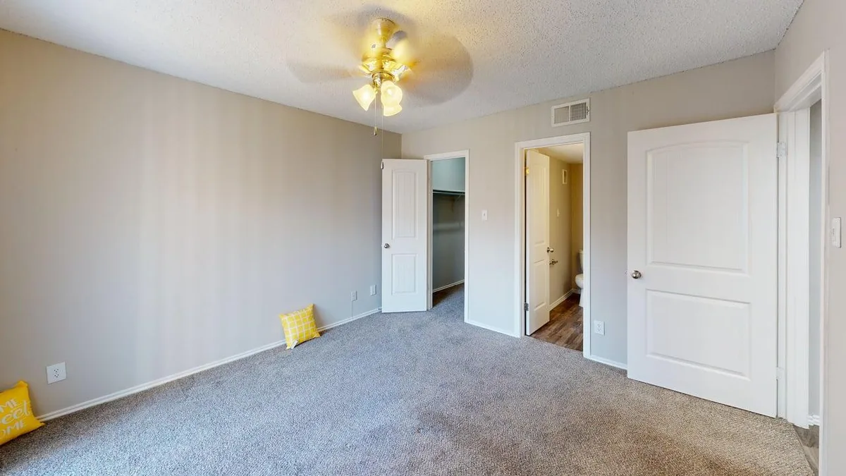 Carpeted bedroom with double doorways to a closet and private bath