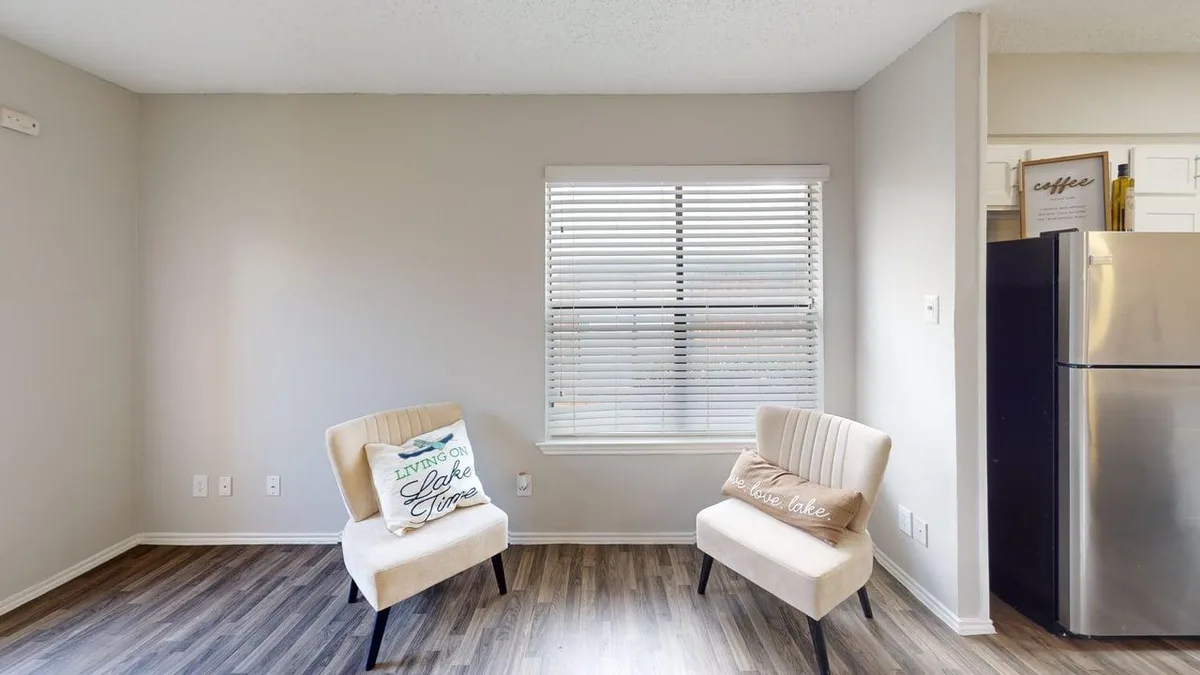 Dining nook with two accent chairs beside a bright window and the kitchen