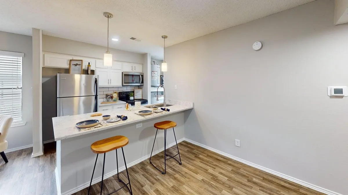 Kitchen with a quartz breakfast bar, pendant lights, and stainless appliances