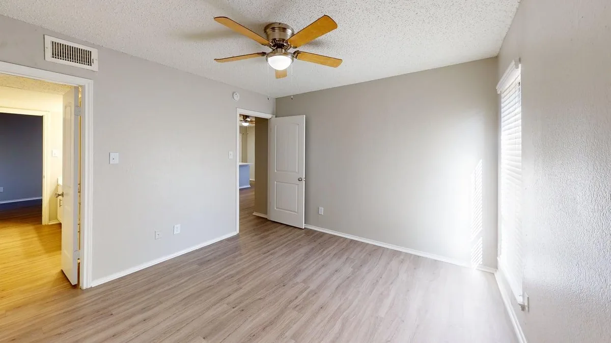 Bedroom with wood-look flooring, a ceiling fan, and access to the hall