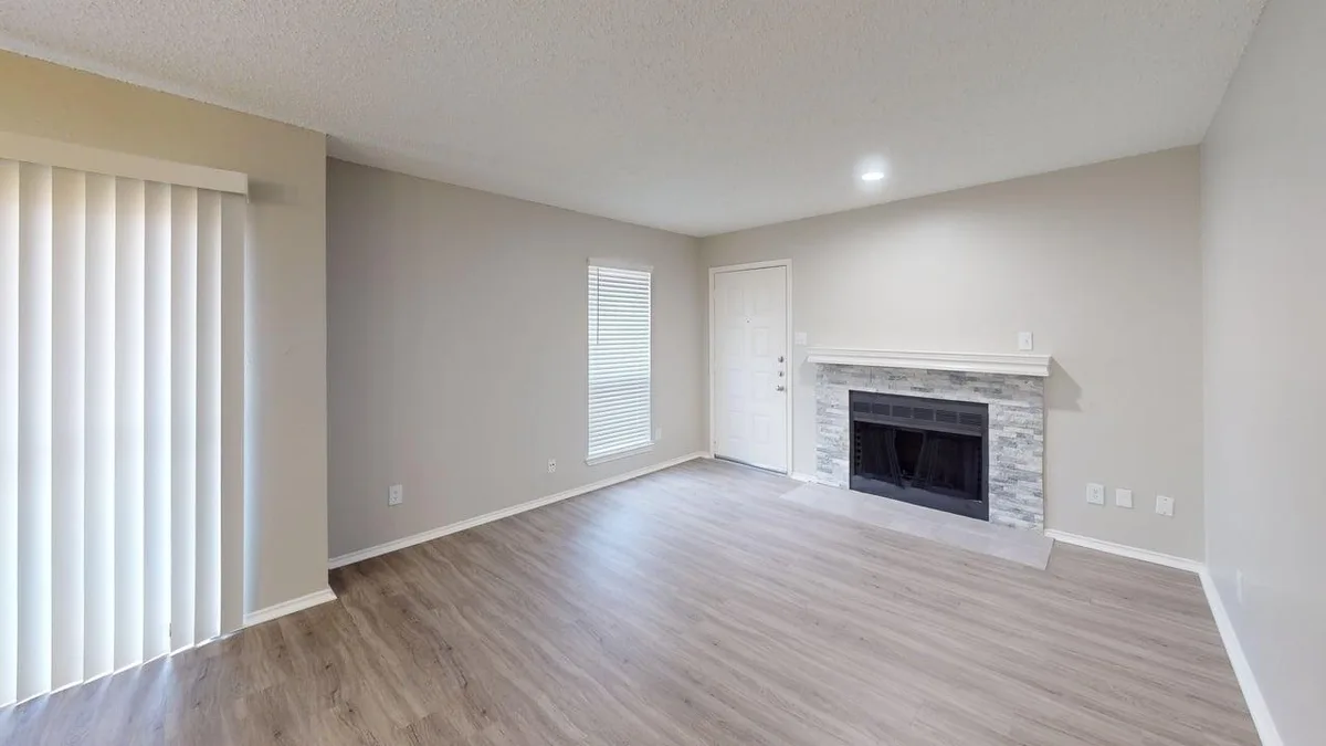 Living room with a stacked-stone fireplace, patio door, and front entry
