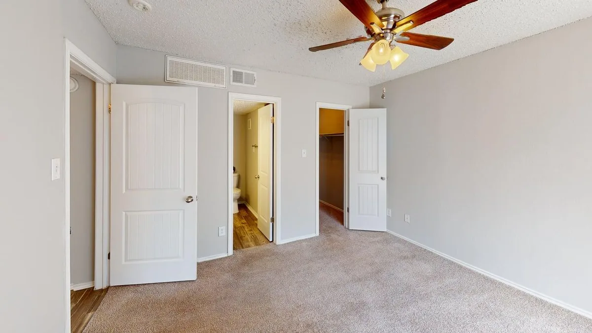 Carpeted bedroom with doorways to an ensuite bath and walk-in closet
