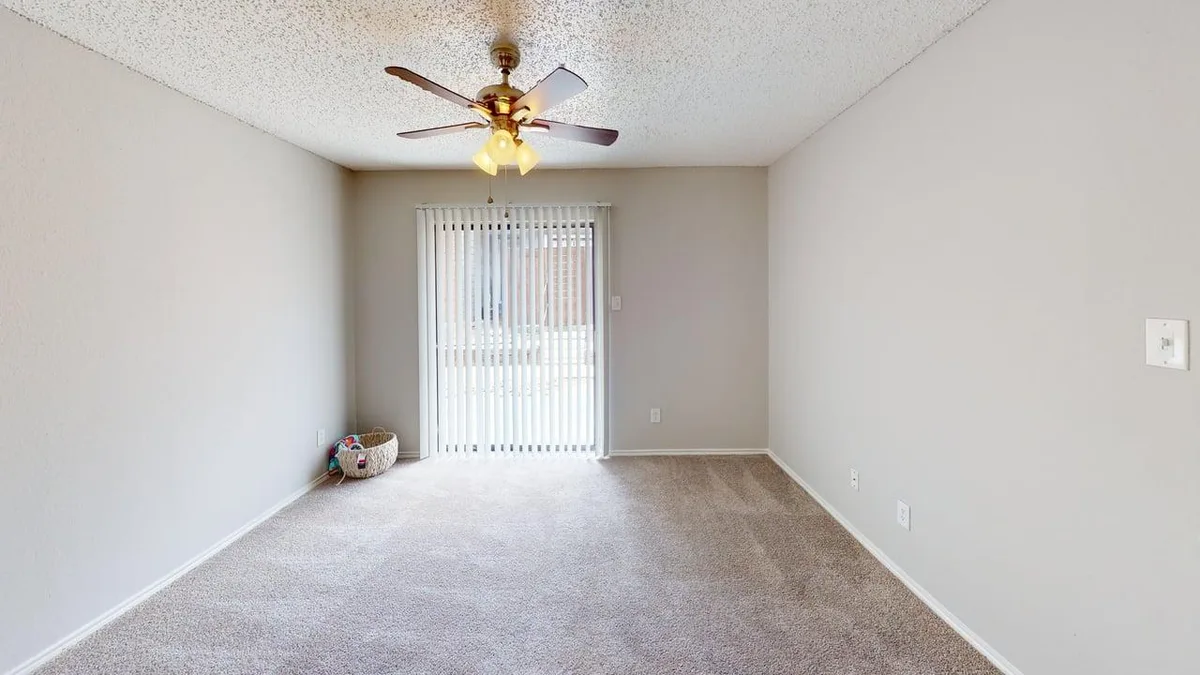 Carpeted bedroom with a sliding glass patio door and a ceiling fan