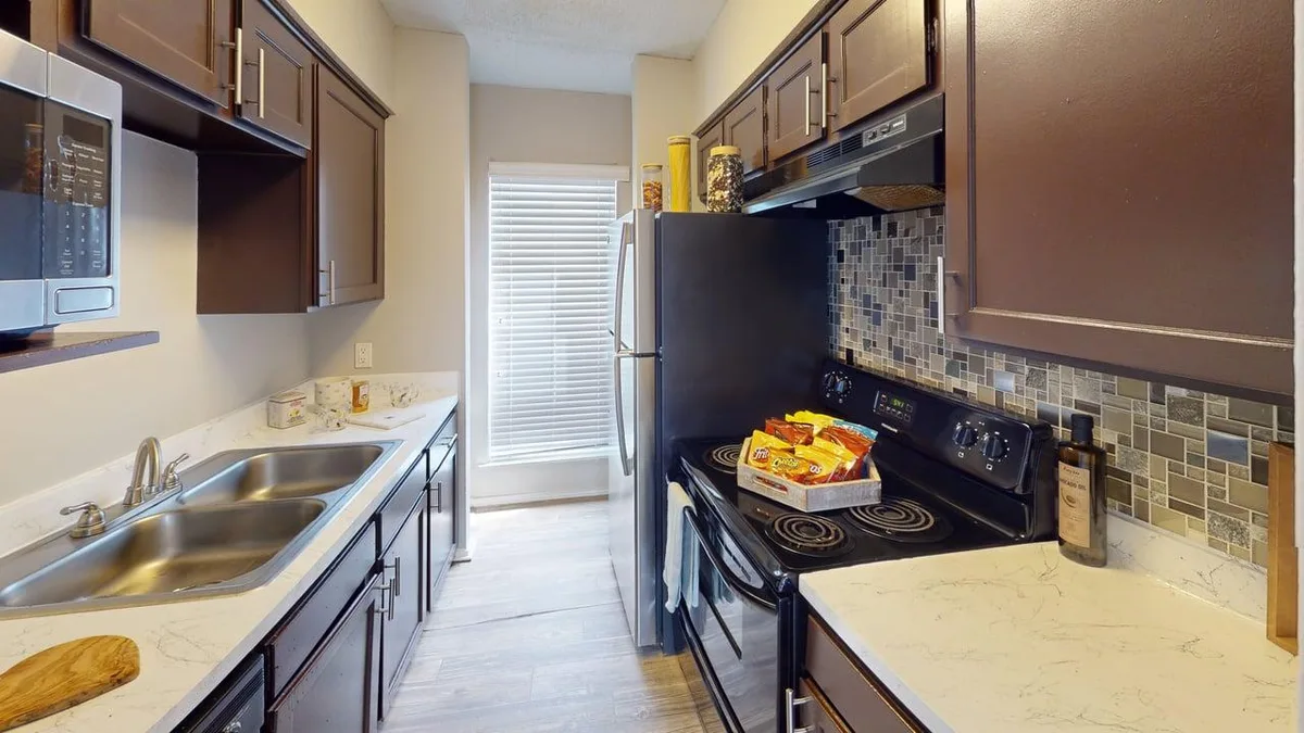 Galley kitchen with espresso cabinets, a mosaic backsplash, and black appliances
