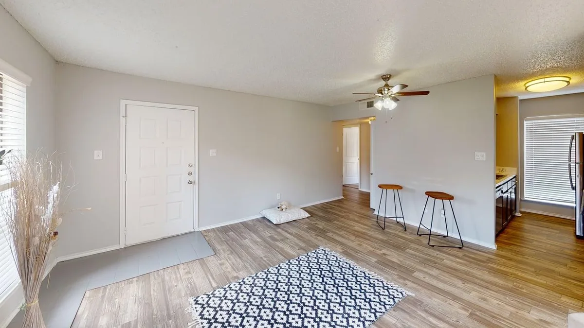 Open living and dining area with a breakfast bar, ceiling fan, and wood-look floors