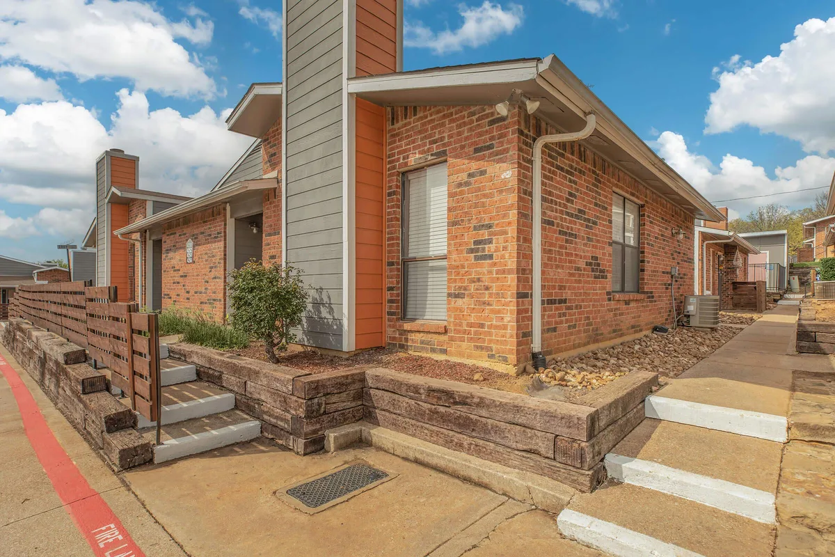Brick apartment building with landscaped stone retaining walls and a paved walkway