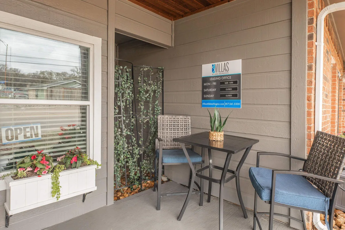 Covered leasing office entrance with patio seating and an open sign