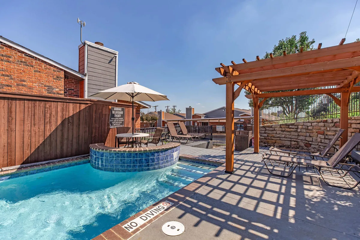 Swimming pool and circular spa enclosed by a wooden privacy fence with shaded seating