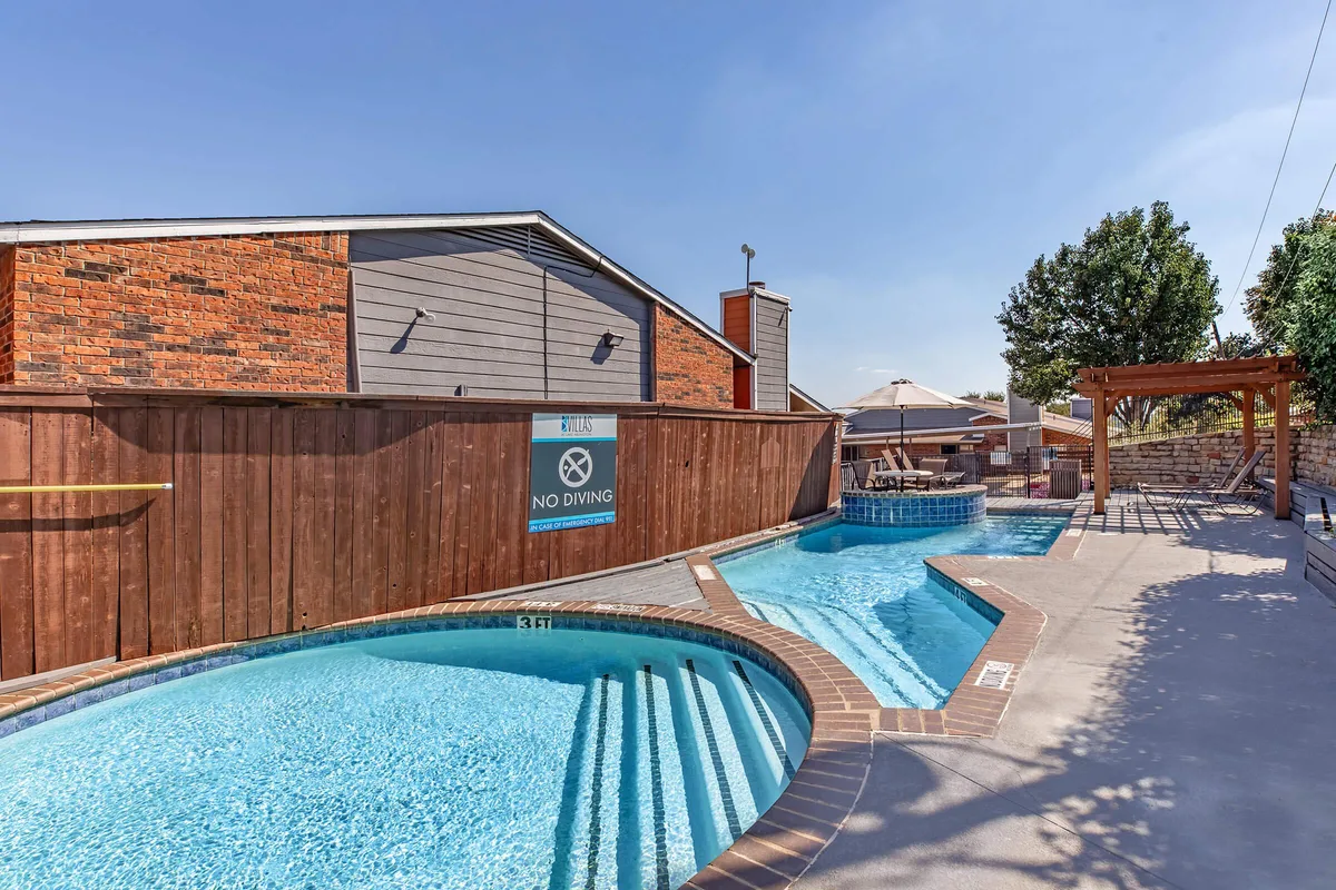 Resort-style swimming pool with tiled edges, a shaded pergola, and lounge seating