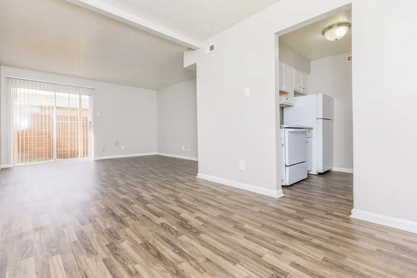 Living area opening to the kitchen with white appliances