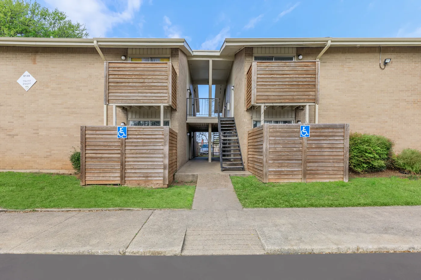 Two-story brick building with wood-screened patios and a central breezeway stair