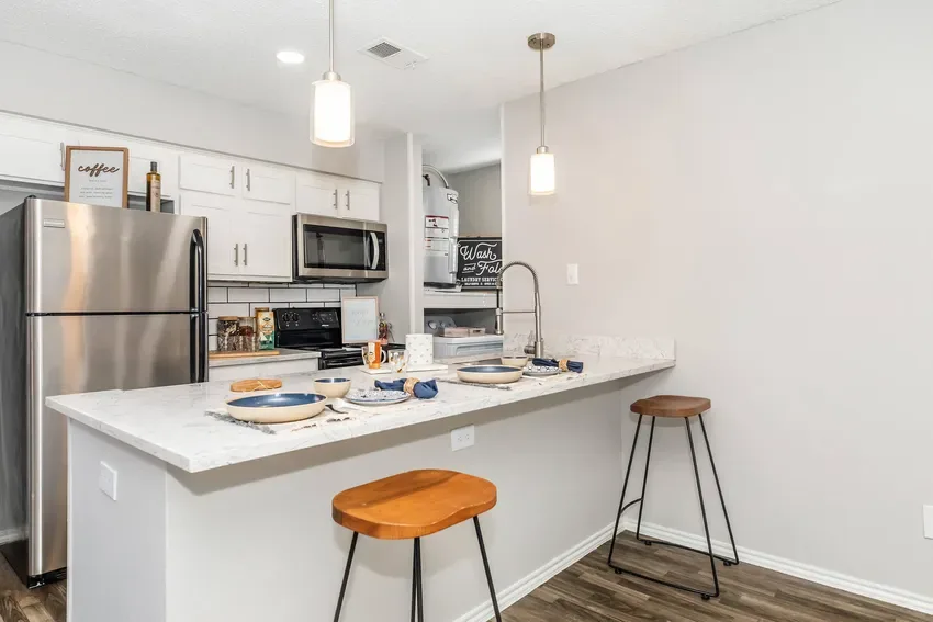 Galley kitchen with a breakfast bar, stainless appliances, and subway-tile backsplash