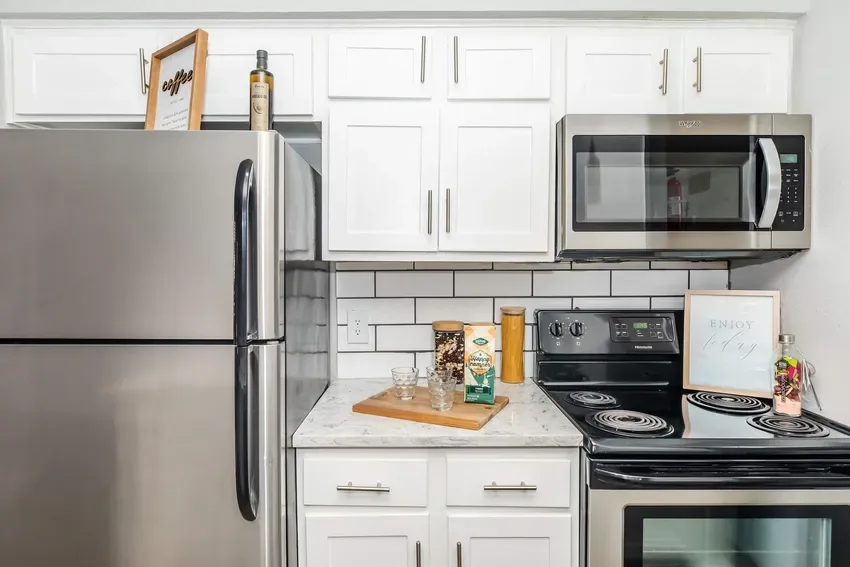 Kitchen with white shaker cabinets, stainless appliances, and subway-tile backsplash