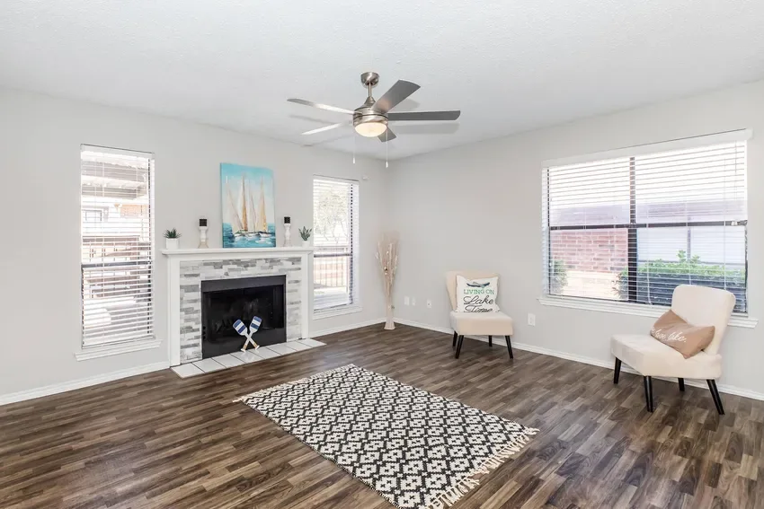 Living room with a tile-surround fireplace, ceiling fan, and wood-look flooring