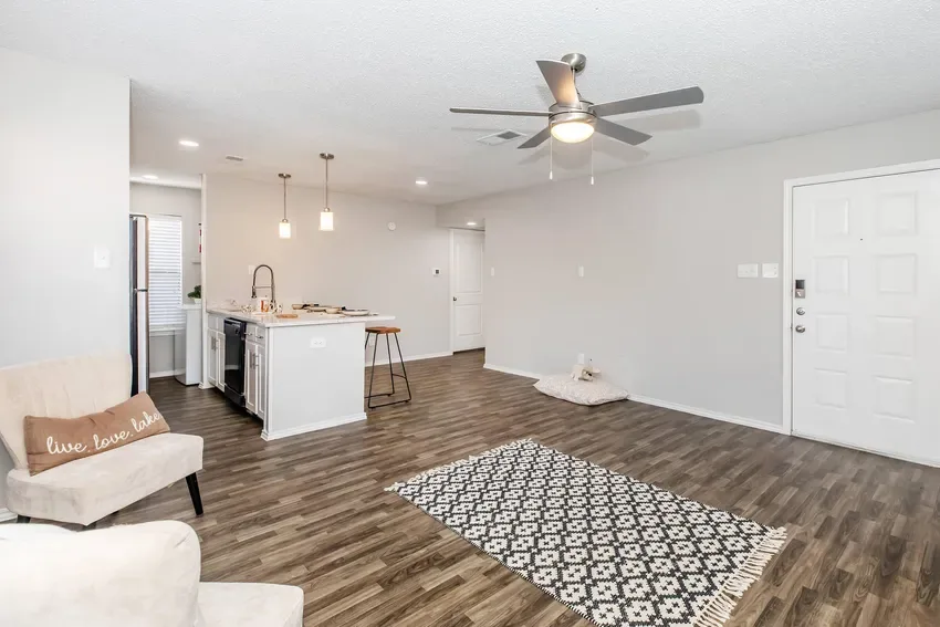 Open living space flowing to a breakfast-bar kitchen with wood-look floors