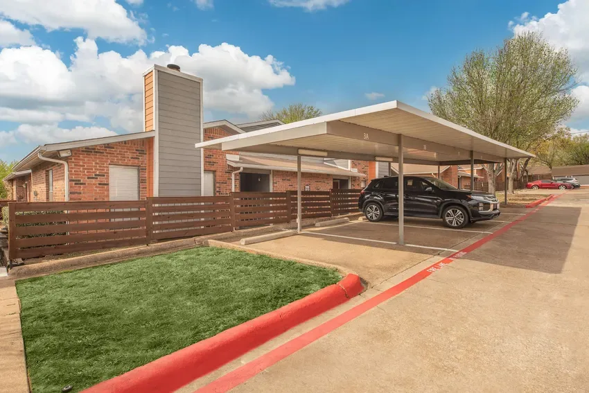 Covered carport parking with red-striped fire lane beside brick residences