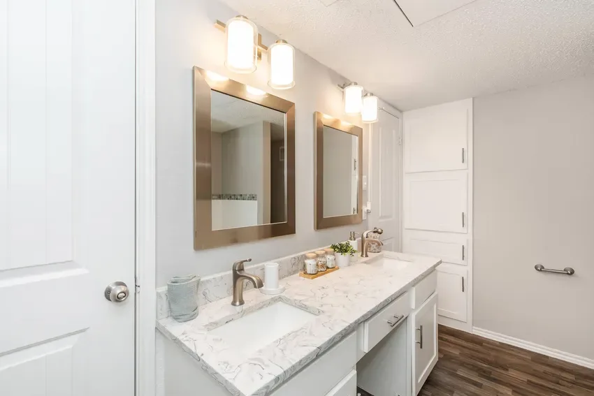 Bathroom with a dual-sink marble-look vanity, framed mirrors, and linen storage