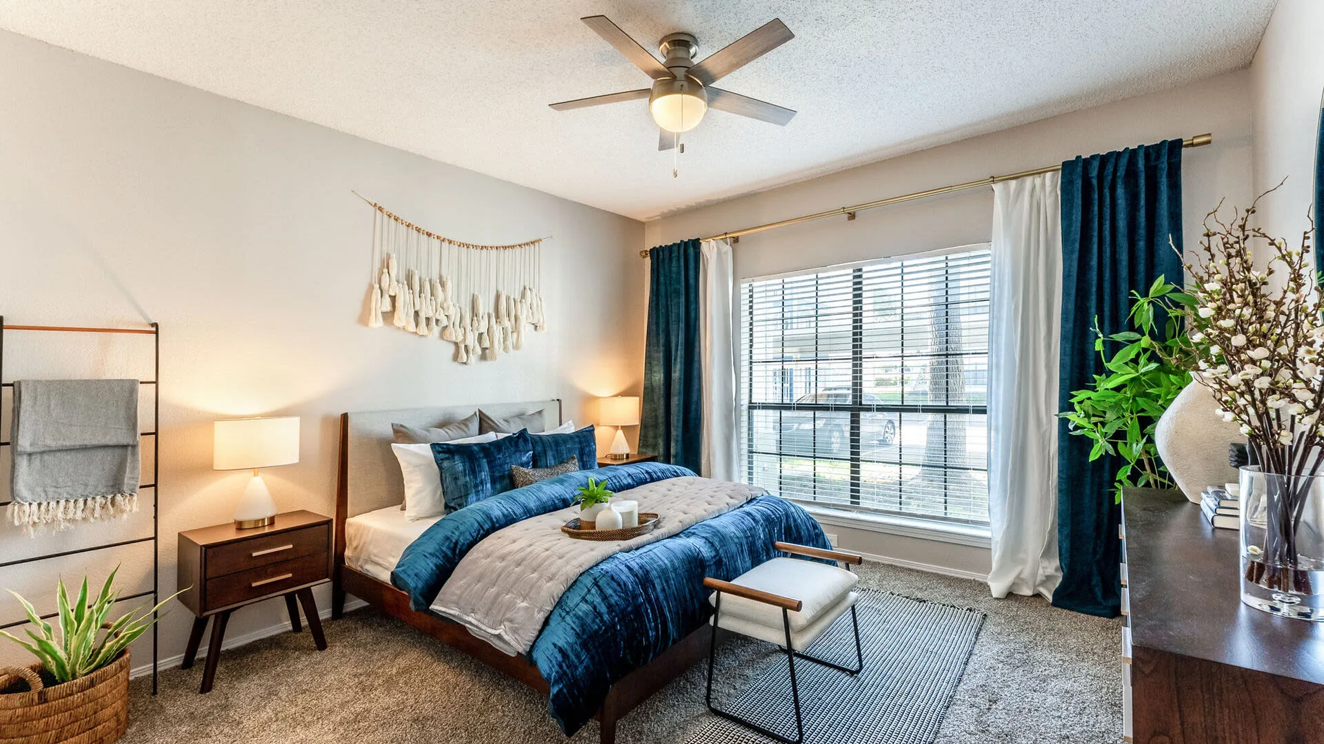 Bedroom with a queen bed, navy bedding, a ceiling fan and a large window