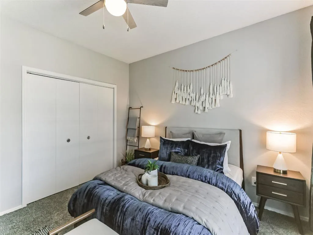Bedroom with an upholstered headboard, macrame wall hanging and twin bedside lamps