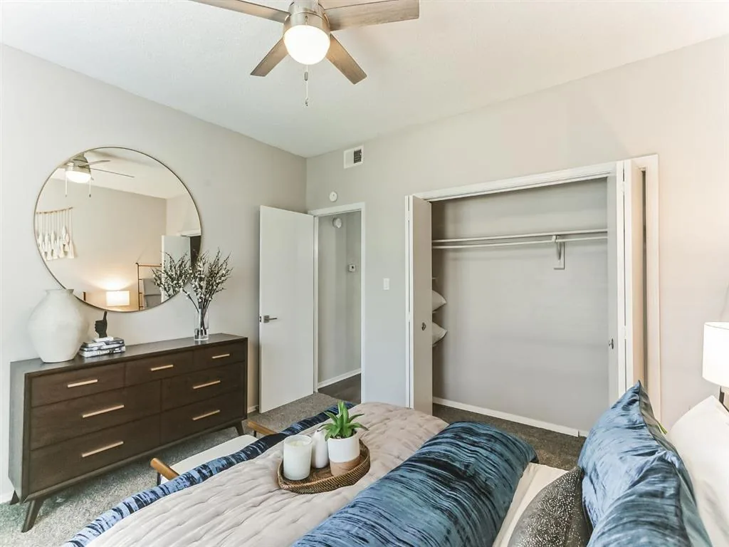 Bedroom dresser and round mirror beside an open walk-in closet