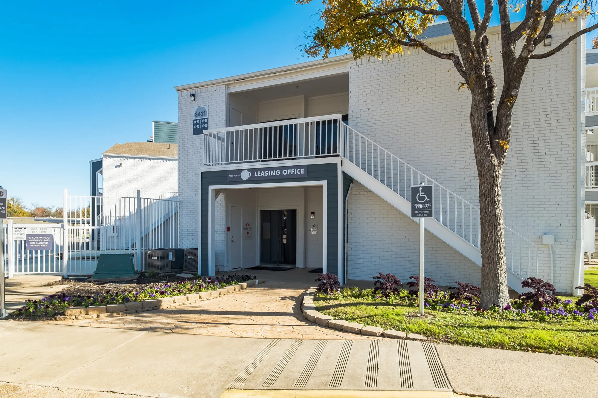 Leasing office entry with white painted brick, a shaded walkway and a bright blue sky