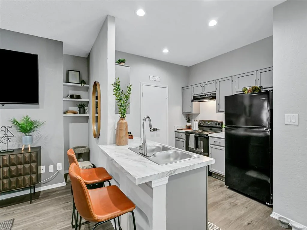 Kitchen island with bar seating, light gray cabinets and black appliances