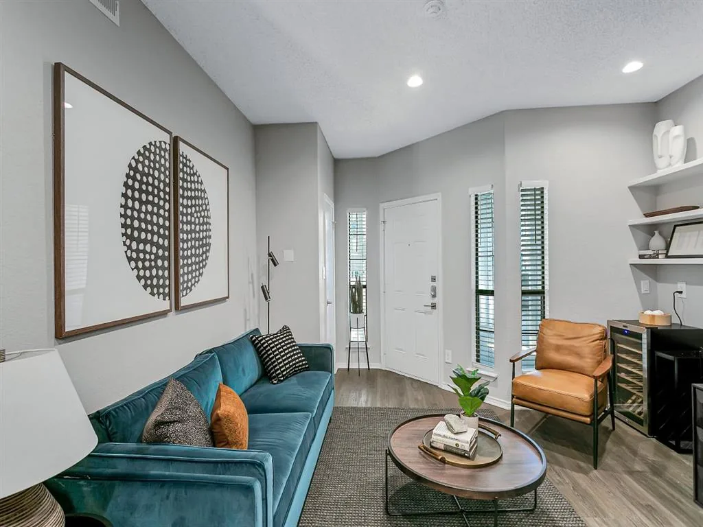 Living room with a teal sofa, two leather chairs and a round coffee table by the patio door