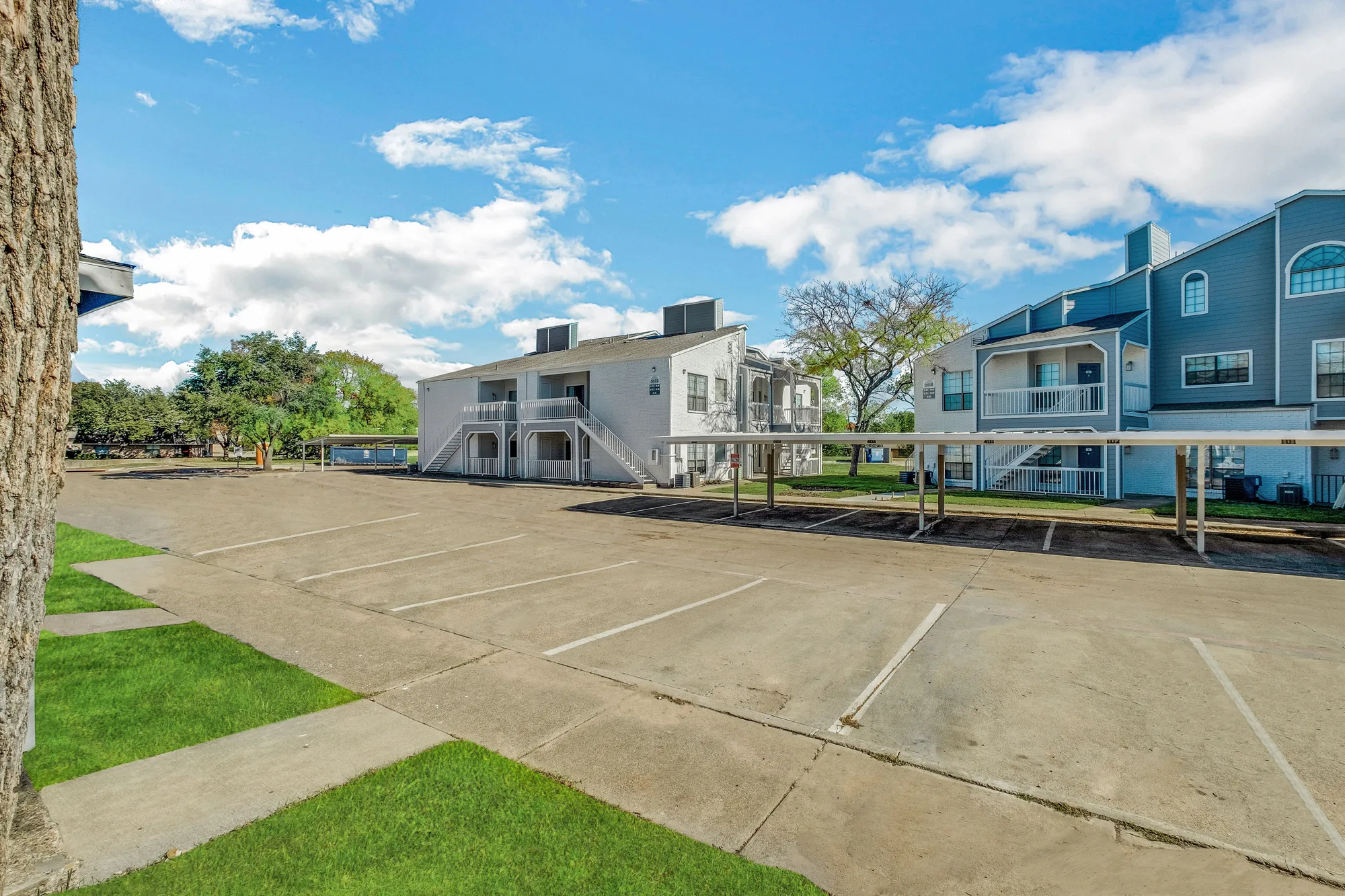 Surface parking and covered carports in front of the two-story buildings